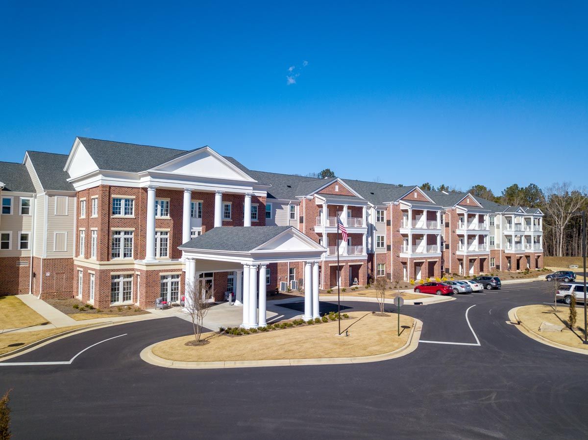A large residential apartment complex with a parking area under a clear blue sky.