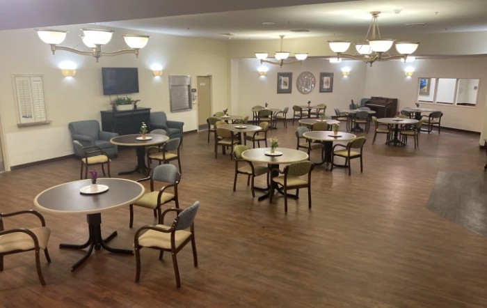 An indoor dining area with multiple tables and chairs arranged evenly across a wooden floor.
