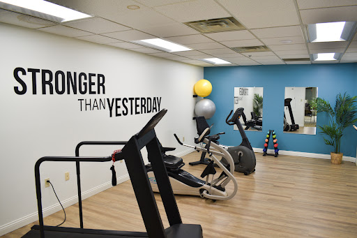A well-equipped gym space featuring various exercise machines and motivational decor.