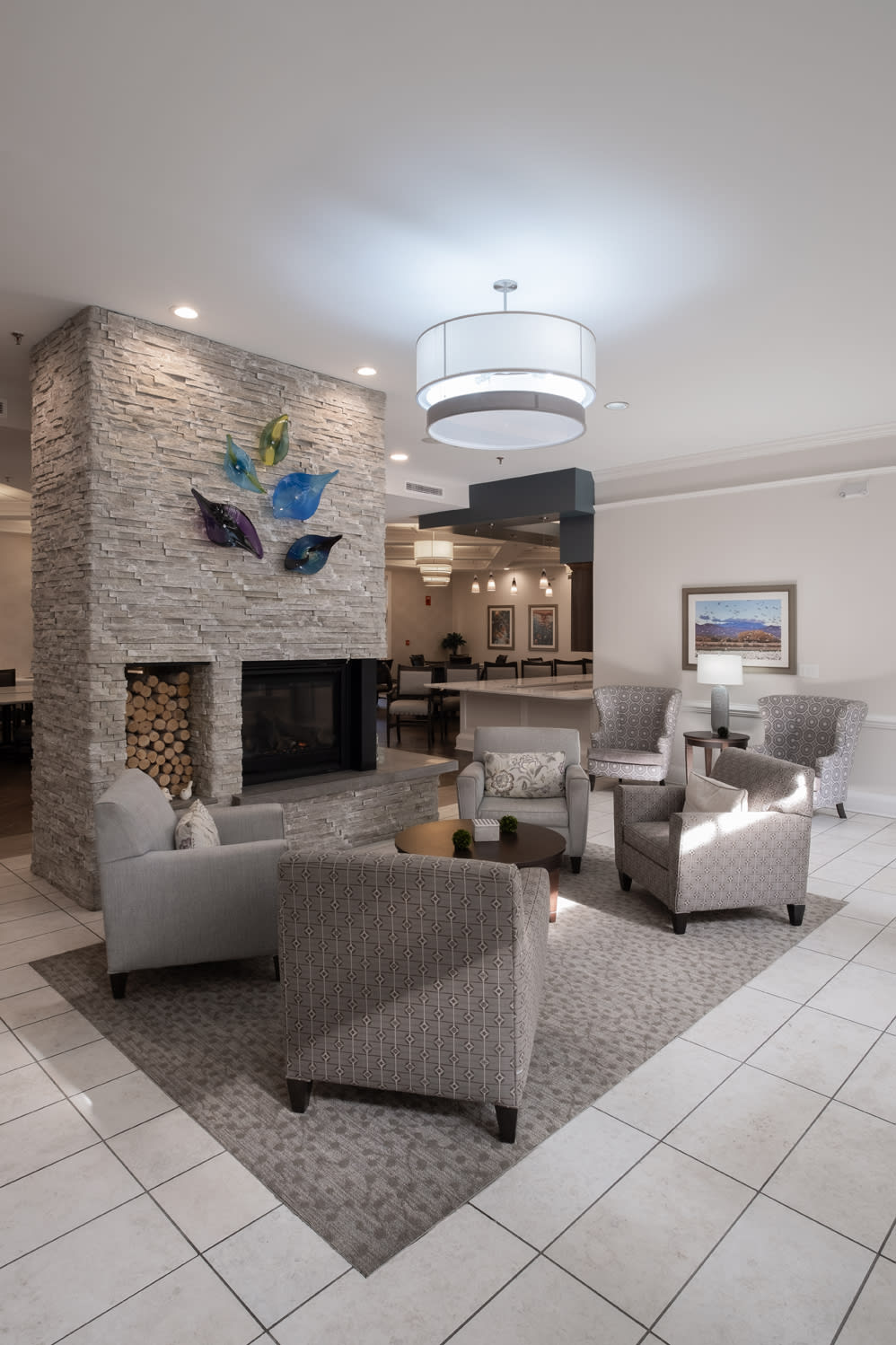 A modern hotel lobby with comfortable seating and a central fireplace.