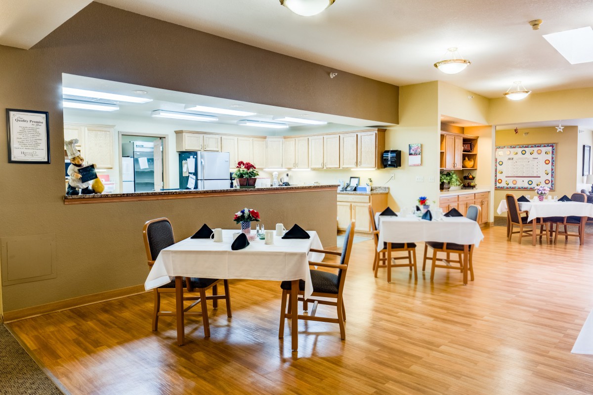 An inviting dining area with neatly arranged tables and chairs next to a kitchen.