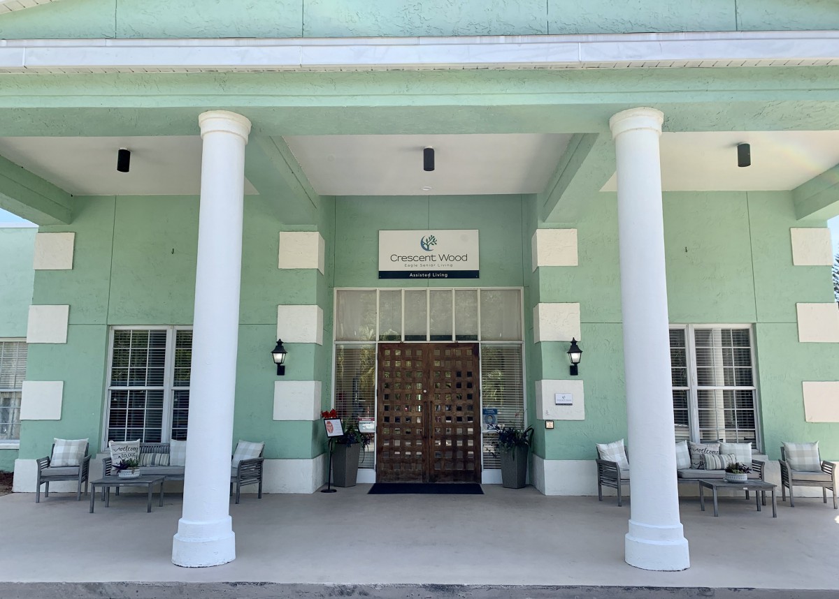 The front entrance of a building with a green exterior and large columns.