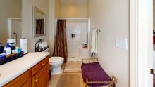 A well-organized bathroom with a shower, toilet, sink, and towels neatly arranged.