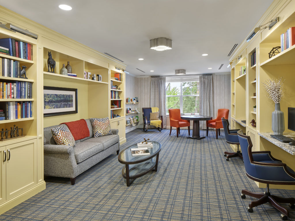 A cozy living room with a sofa, bookshelves, and a table surrounded by chairs.