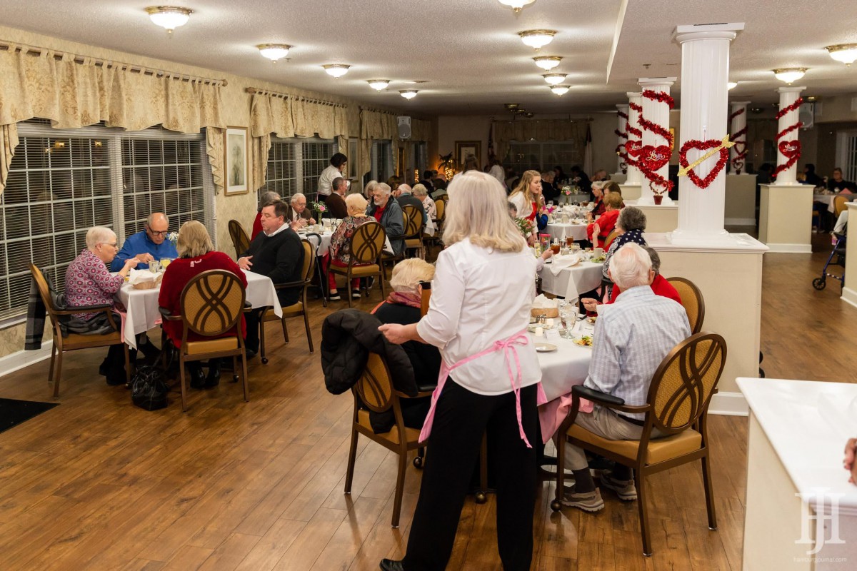 A cozy indoor dinner gathering with guests seated at tables in a warmly decorated room.