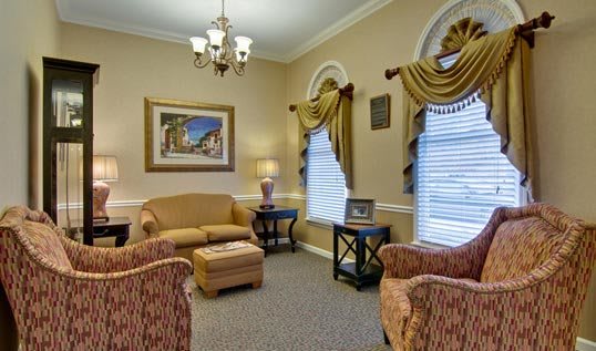 A traditionally decorated living room featuring a sofa, chairs, and elegant curtains.