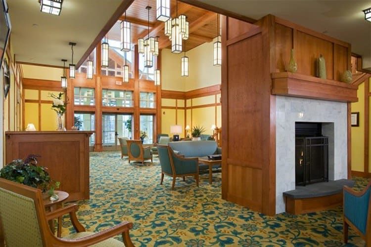 A spacious hotel lobby with elegant wood paneling, comfortable seating areas, and large windows providing ample natural light.