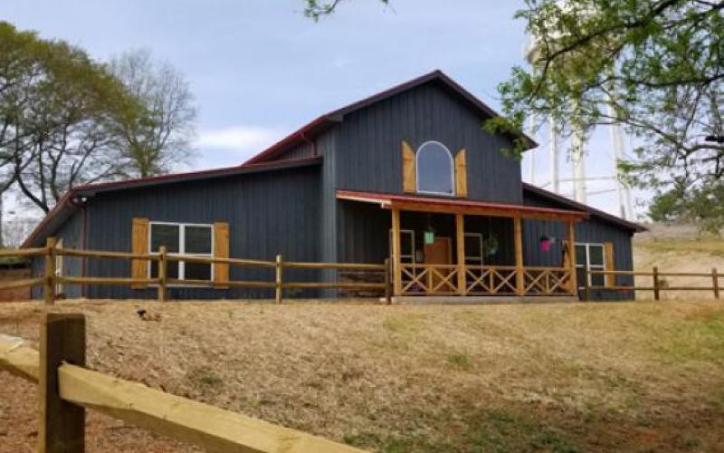 A rustic barn with a wooden exterior and surrounding fence.