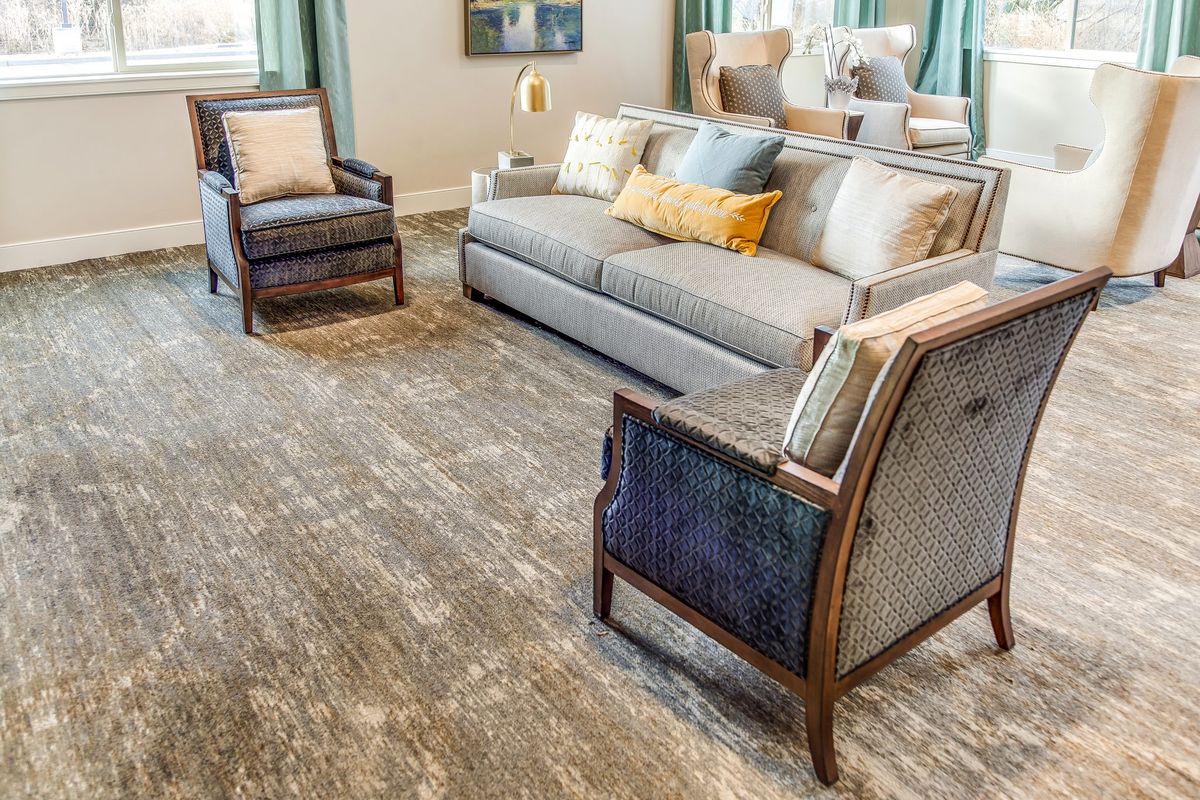 A cozy living room with a grey sofa, two armchairs, and a textured carpet.