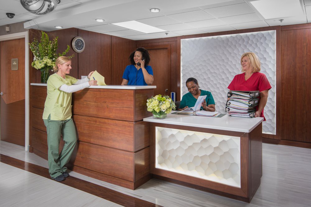 Employees at a reception desk in a medical office setting.