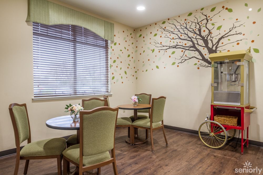 A cozy dining area with elegant chairs and a tree-themed wall design.