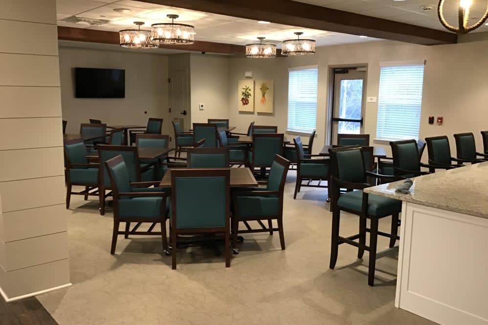 A well-furnished dining room with several tables and chairs arranged neatly under elegant lighting.