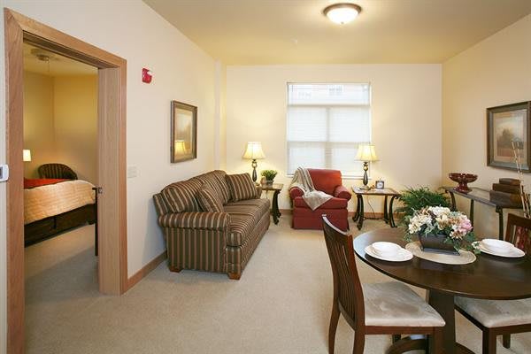 A cozy living room with a sofa, armchair, and dining table.