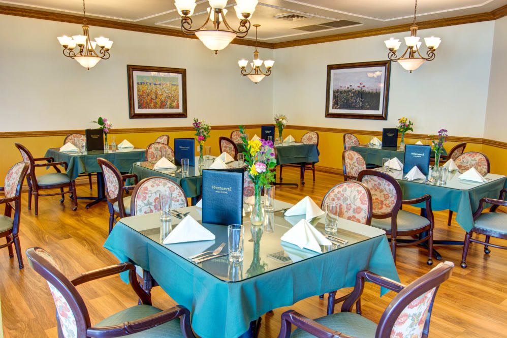 A well-decorated dining room with neatly arranged tables and elegant chandeliers.