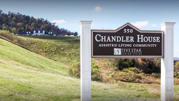 A sign for Chandler Place Assisted Living Community set against a grassy landscape.