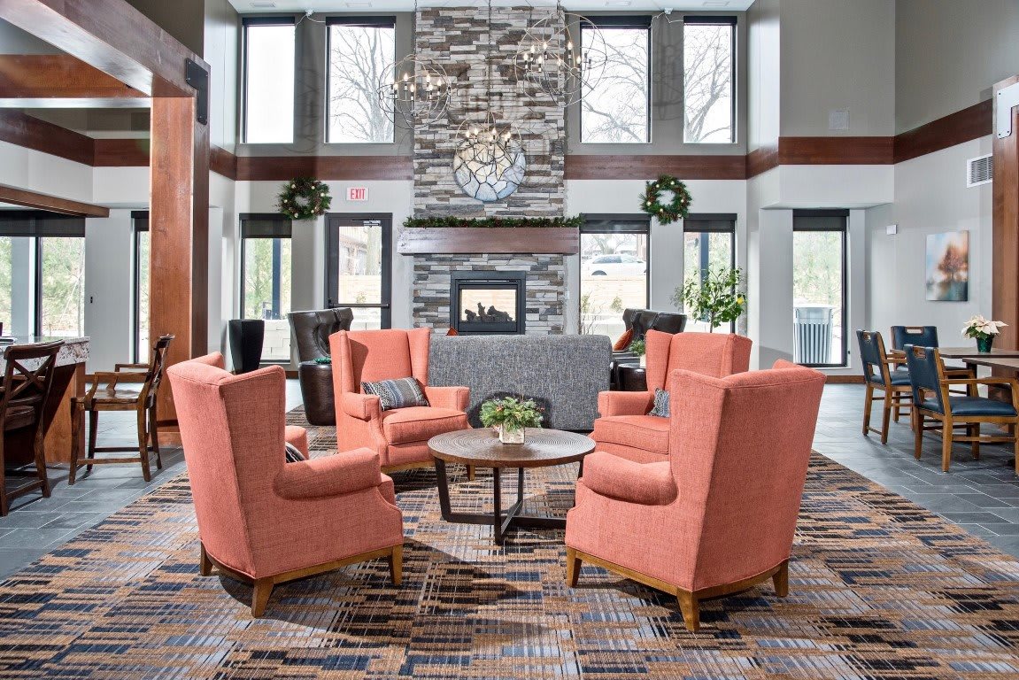 A modern lounge area with coral chairs surrounding a coffee table in front of a stone fireplace.