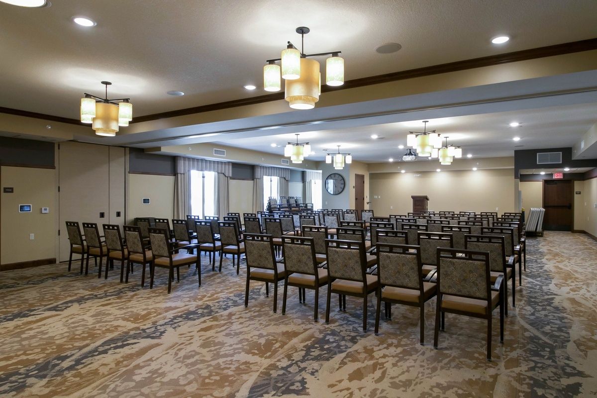 An empty conference room set up with rows of chairs and overhead lighting.