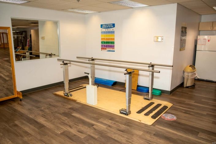 A physical therapy room featuring parallel bars and exercise equipment for rehabilitation.