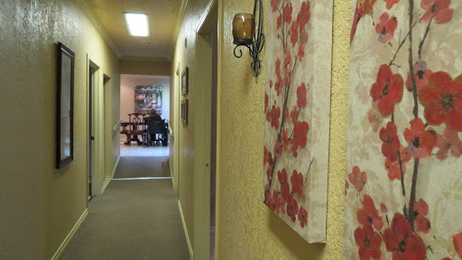 A view of a cozy hallway adorned with floral artwork, leading to a warmly lit room.