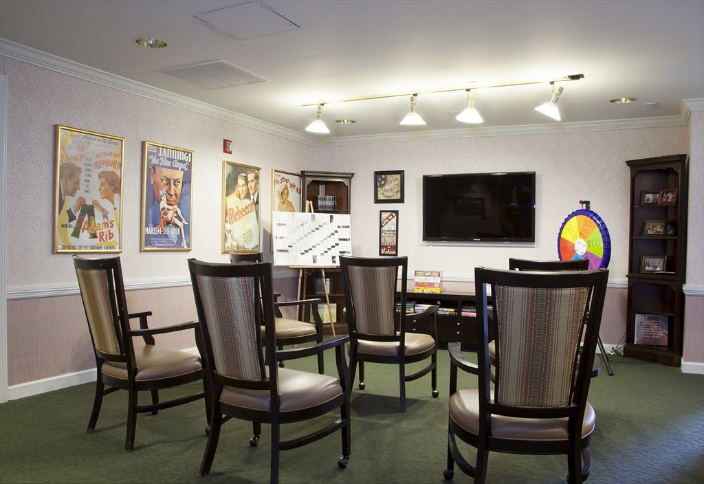 A well-lit conference room with arranged chairs, a television, and artwork on the walls.