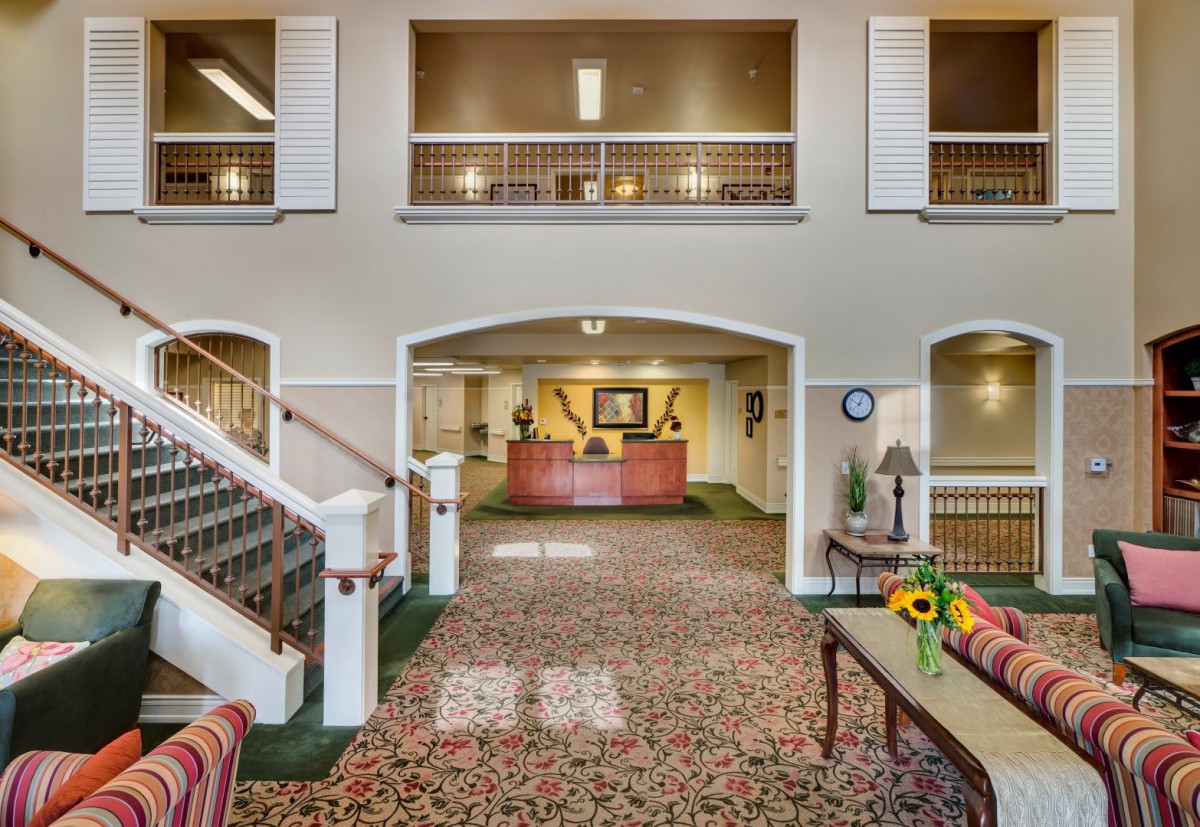 A spacious hotel lobby with a reception desk, carpeted floors, and elegant interior design.