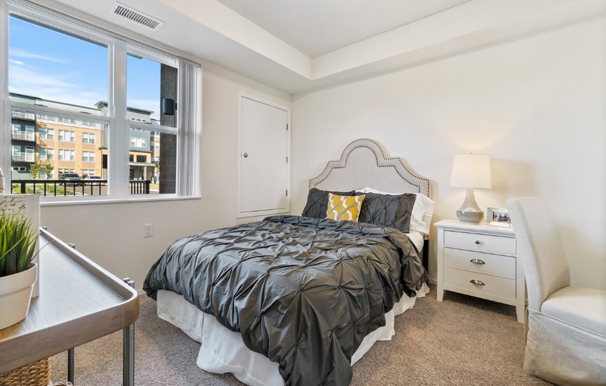 A cozy bedroom with a neatly made bed, stylish headboard, and elegant bedside lamp.