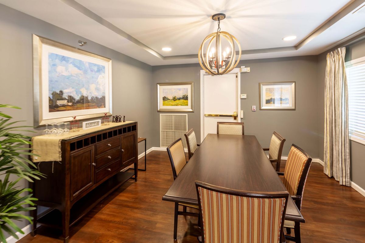A modern dining room with a wooden table, upholstered chairs, and a stylish chandelier.