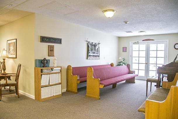 A waiting room with wooden benches, a bookshelf, and wall decor.