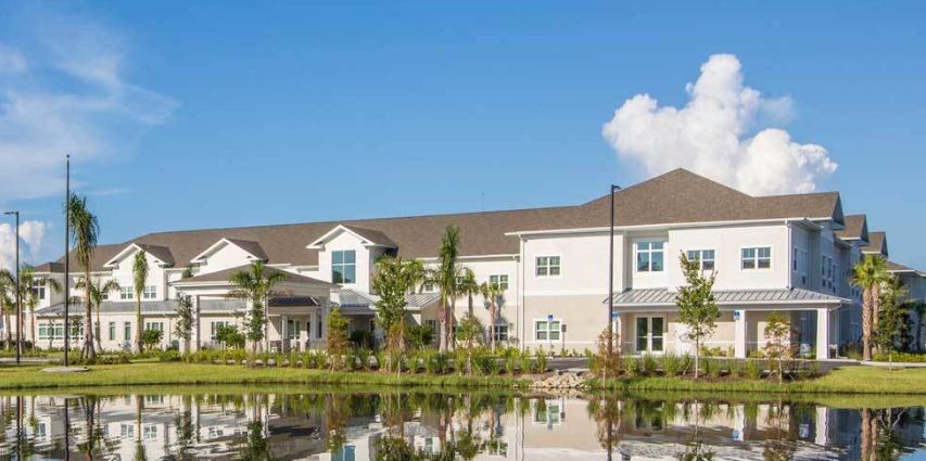 A residential building by a tranquil lake with a clear blue sky.