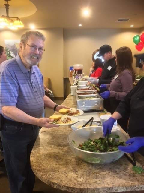 People at a buffet line receiving food from servers.