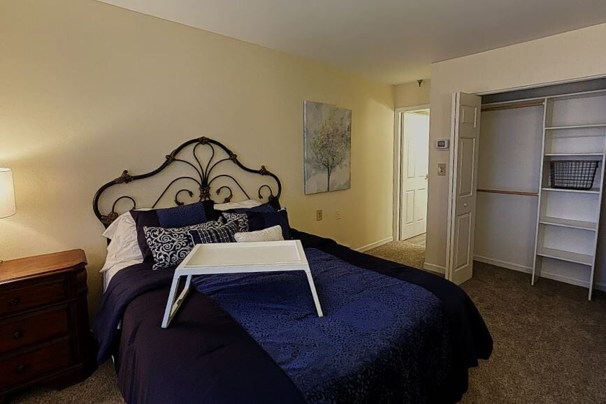 A cozy bedroom with a decorative bed and a tray table on top.