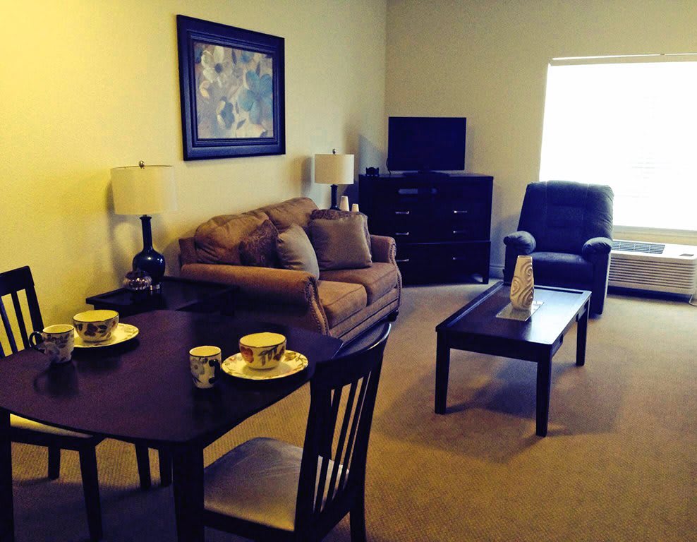 A cozy living room with a sofa, armchair, and a small dining area.