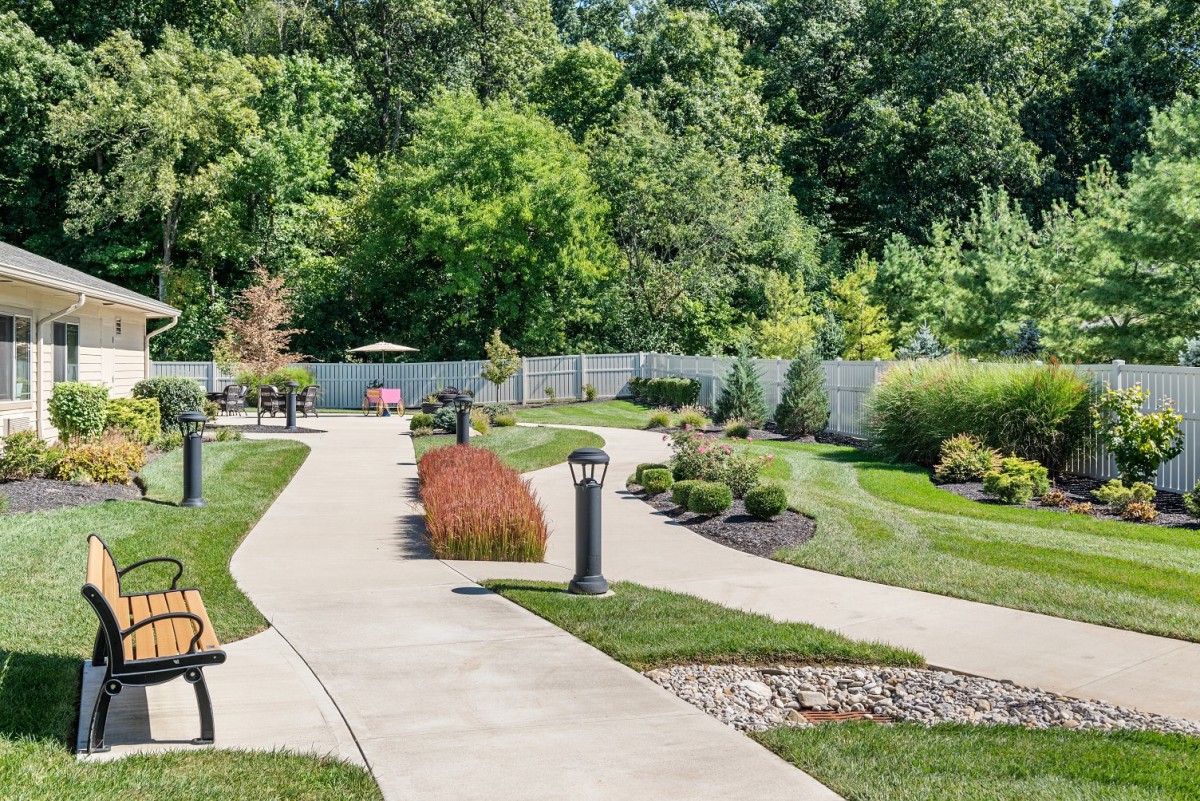 A beautifully landscaped garden featuring a winding pathway surrounded by lush greenery and well-maintained lawns.
