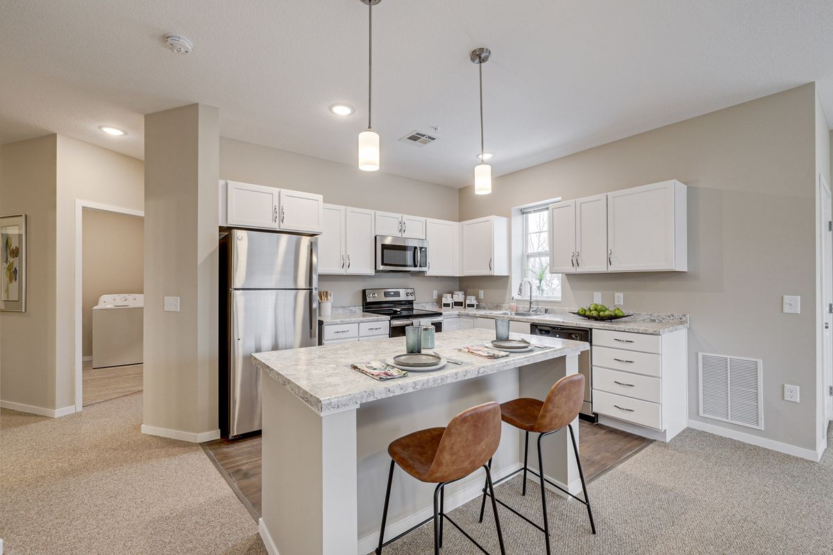 Modern kitchen with a central island, stainless steel appliances, and stylish lighting.