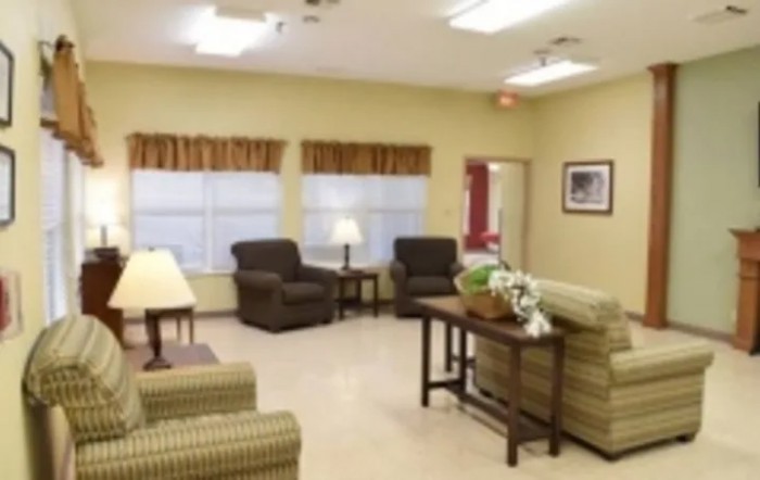 A cozy living room with armchairs, a sofa, a table, and lamps.