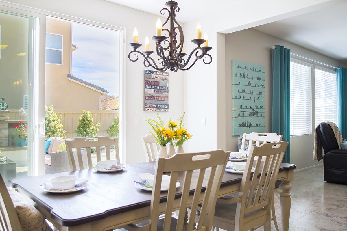 A well-lit dining room with a wooden table, chairs, and a decorative chandelier.