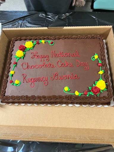A delicious chocolate cake decorated with colorful flowers and a special message for a celebration.
