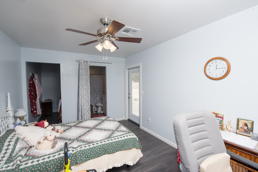 A cozy and well-lit bedroom featuring a ceiling fan, a bed with an intricate quilt, and modern decor.