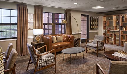 A cozy living room with modern furnishings, including a leather sofa, stylish chairs, coffee table, and elegant lighting.