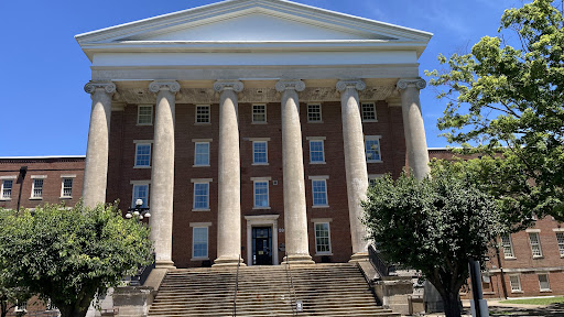 A grand brick building featuring prominent columns and a well-structured facade, inviting visitors up the steps to its entrance.