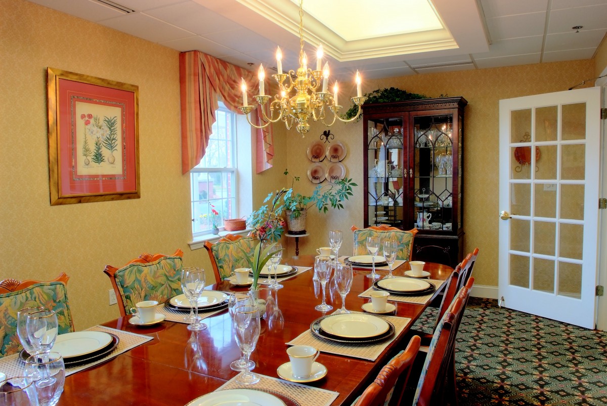 A well-appointed dining room with a chandelier, elegant table settings, and a china cabinet.