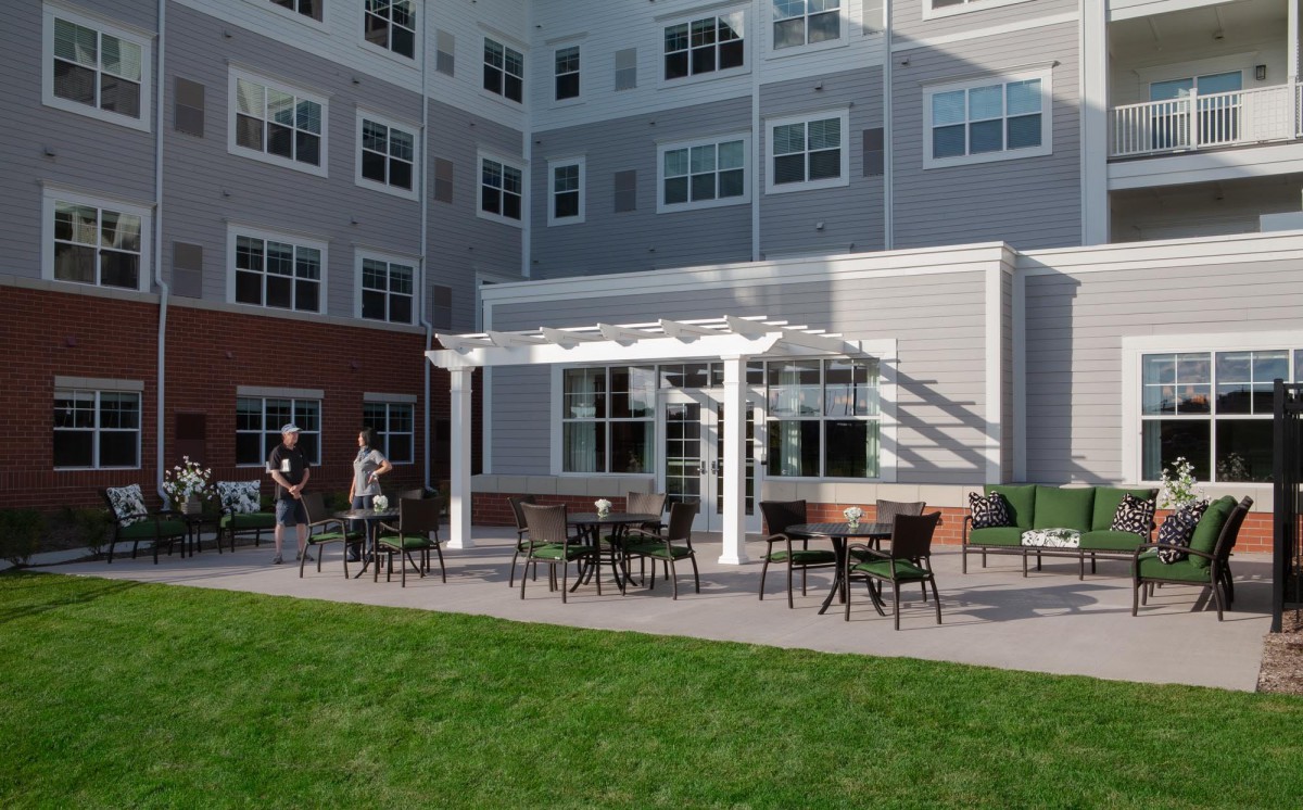 An outdoor patio area with tables and chairs, located next to a modern building.