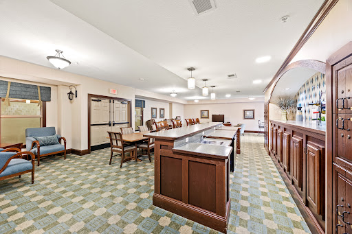 A spacious and well-lit lobby area featuring a wooden bar and elegant dining furniture.