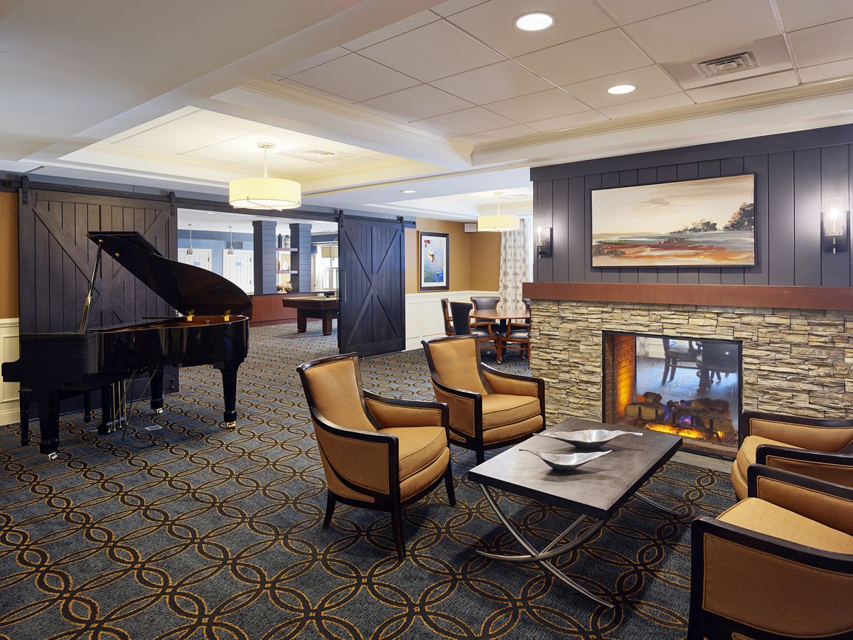 A cozy hotel lounge featuring a fireplace, piano, and comfortable seating.