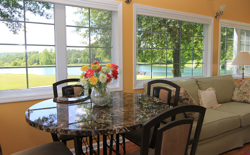 A bright and inviting dining area with a beautiful lake view, featuring a floral centerpiece on the table.