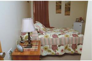A cozy bedroom with floral patterned bedding and a wooden nightstand.