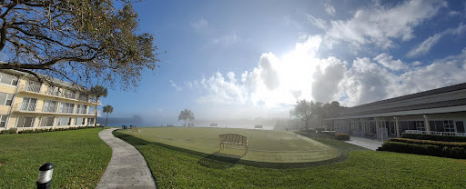 A serene park scene with a bench overlooking a misty landscape under a bright sky.