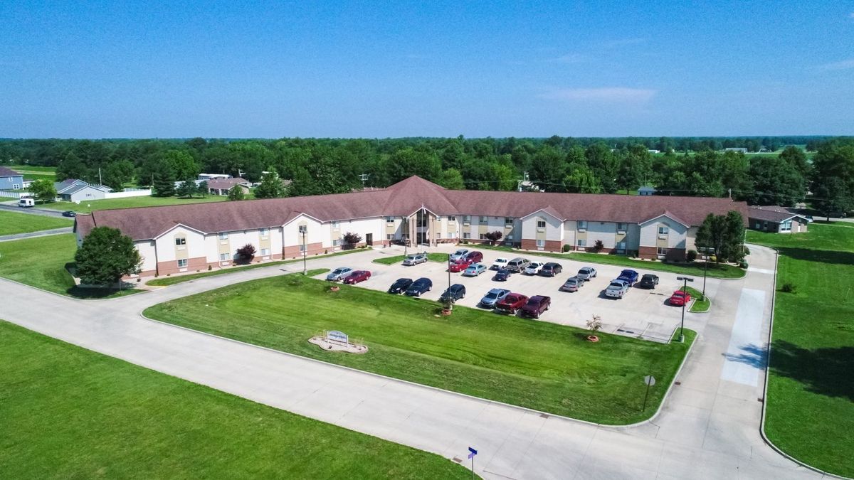 Aerial view of a large building with a parking lot surrounded by greenery.