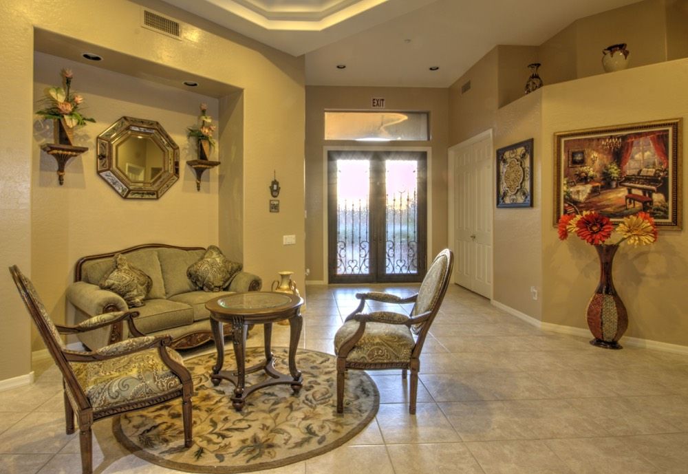A cozy living room with elegant furniture and decor, featuring a sofa set, chairs, and a round table on a decorative rug near the entrance.
