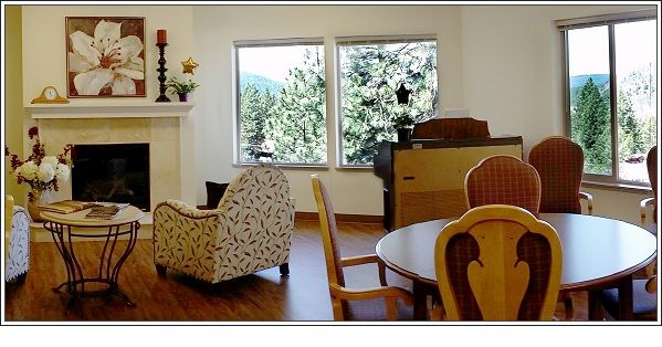 A cozy living room with a fireplace, piano, and large windows overlooking the outdoors.